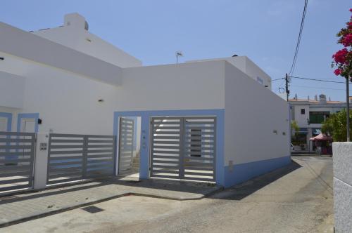 a white building with a door and a fence at MORADIA NOVA E COMPLETA A 350 MTRS. PRAIA in Vila Nova De Cacela