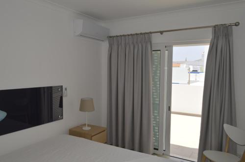 a bedroom with a bed and a sliding glass door at MORADIA NOVA E COMPLETA A 350 MTRS. PRAIA in Vila Nova de Cacela