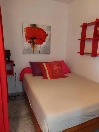 - une chambre dotée d'un lit avec des oreillers rouges et un tableau dans l'établissement AJACCIO SANGUINAIRES APPT 3 P POUR 4 A 5 PERSONNES TTES COMMODITÉS TT CONFORT ! A 300M DES PLAGES ET A 5 MN DU CENTRE VILLE, à Ajaccio