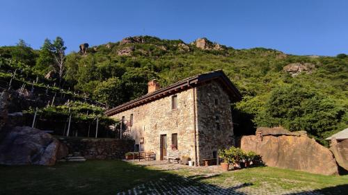 a stone house in front of a mountain at B&B Al Vecchio Torchio in Settimo Vittone