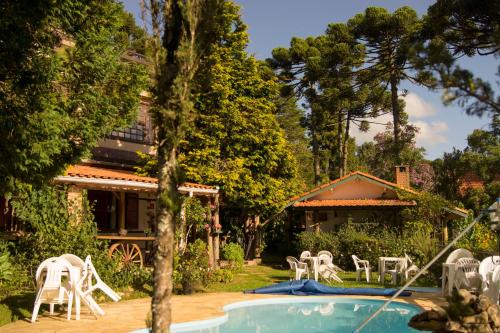 um quintal com uma piscina com cadeiras e uma casa em Pousada Locanda Belvedere em Monte Verde