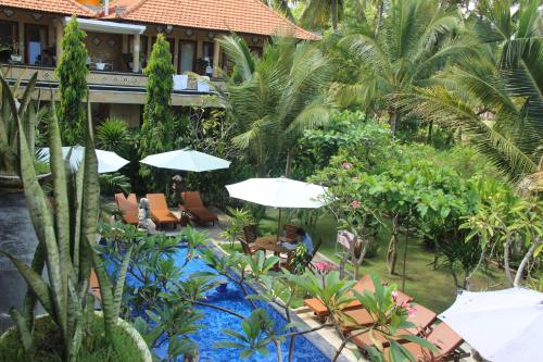 a resort with a swimming pool with chairs and umbrellas at Nitya Home Stay Lembongan in Nusa Lembongan
