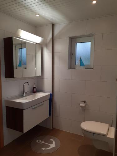 a bathroom with a sink and a toilet and a mirror at Ferienwohnung Am Ostfriesland-Wanderweg in Rhauderfehn