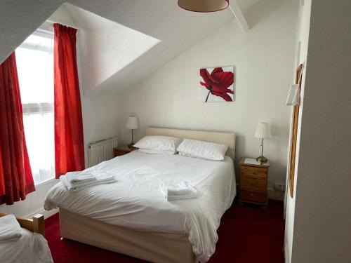 a bedroom with a white bed and red curtains at Robyn's Guest House in Scarborough