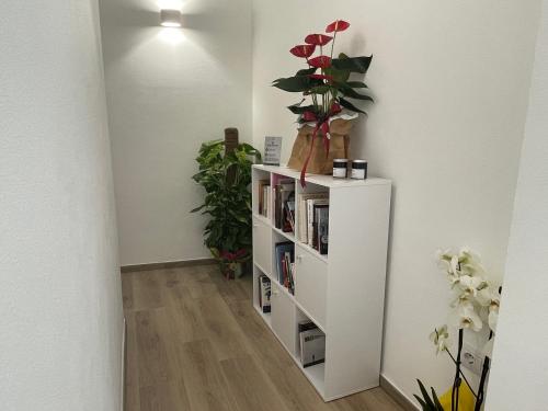 a white book shelf with flowers on top of it at Admayora Guest House in Villasimius