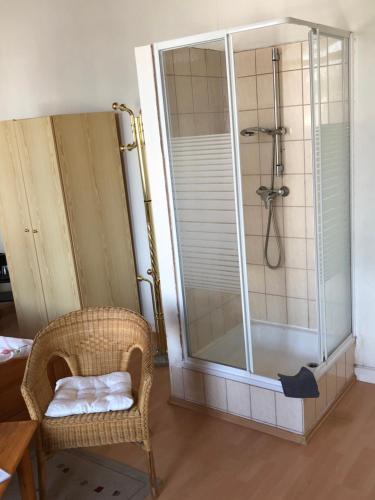 uma casa de banho com um chuveiro e uma cadeira de vime em Pension „La Rose“ em Norden