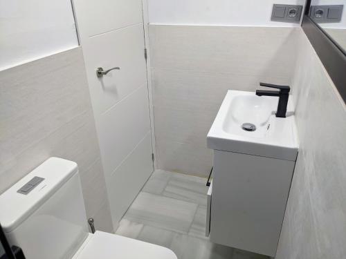 a white bathroom with a sink and a toilet at Salobreña - Primera Línea de Playa junto al Paseo Marítimo in Salobreña