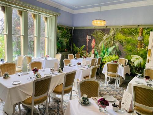 ダラムにあるFarnley Tower Guesthouseの白いテーブルと椅子、植物のあるレストラン