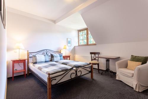 a bedroom with a bed and a chair and a window at Penzion Bavaria in Mariánské Lázně