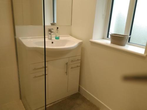 een witte badkamer met een wastafel en een douche bij 43 Reidhlean Clifden Glen in Galway