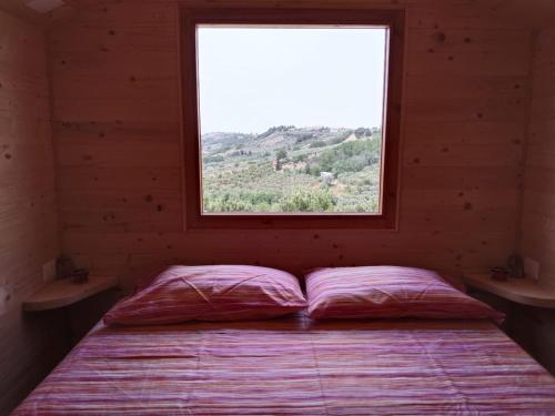 Ce lit se trouve dans une chambre en bois dotée d'une fenêtre. dans l'établissement La casetta sotto l'albero LA CAROVANA GITANA, à Vasto