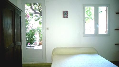 une chambre blanche avec un lit et une fenêtre dans l'établissement Logement climatisé avec jardin et parking pour 2 personnes en bord de plage, à La Ciotat