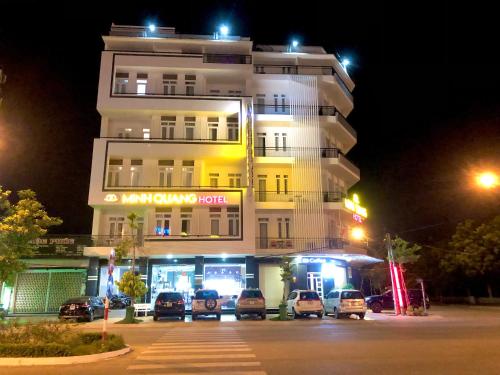 un bâtiment avec des voitures garées devant lui la nuit dans l'établissement Khách sạn Minh Quang, à Phan Rang