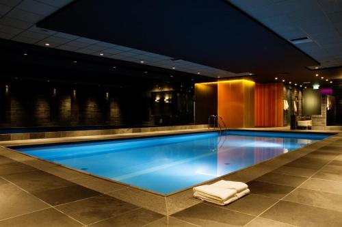 a swimming pool in a hotel with a lounge chair at Fletcher Hotel-Restaurant Oud London in Zeist