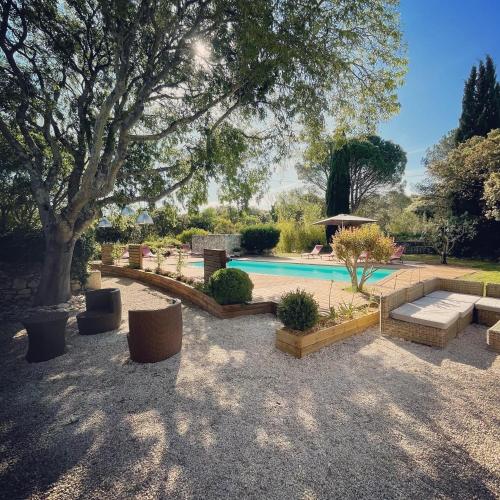une cour avec une piscine bordée de canapés et d'arbres dans l'établissement Le Mas du Bout, à Eygalières