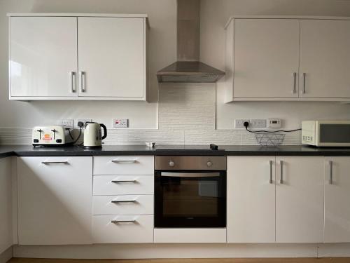 una cocina blanca con armarios y electrodomésticos blancos en Woodside retreat holiday home in Aviemore, en Aviemore