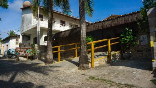 a yellow fence in front of a building with palm trees at Xamã Senses - Hotel Pousada in Pipa