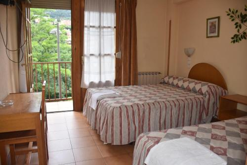 a hotel room with two beds and a balcony at Hotel Tres Arcos in San Lorenzo de El Escorial