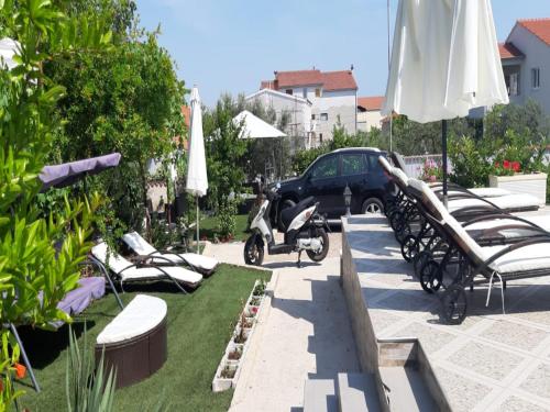 a group of lawn chairs and umbrellas and a car at Vodice Guesthouse in Vodice