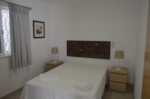 a bedroom with a bed with white sheets and two lamps at Casas da Nespereira, V1 a 350 mtrs. praia in Vila Nova De Cacela