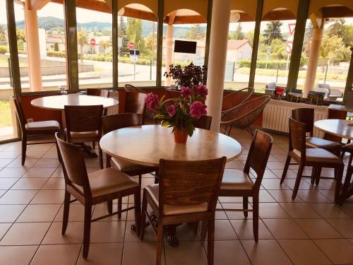 un restaurant avec des tables et des chaises avec des fleurs dessus dans l'établissement Abel Hôtel, à Langeac