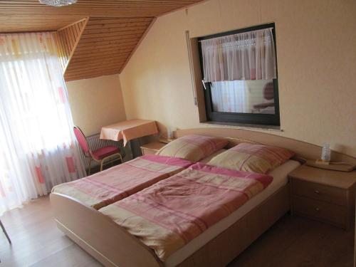 a bedroom with a bed and a table and a window at Pension Simon in Reil