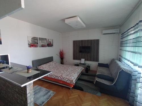 a bedroom with a bed and a desk and a couch at Apartman Bolero in Bijeljina
