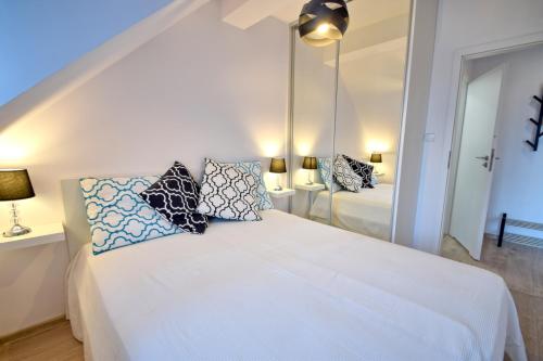 um quarto com uma cama branca com almofadas e um espelho em Apartament z widokiem, osiedle FENIKS em Kolobrzeg