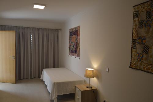 um quarto com uma cama e um candeeiro em Moradia V2 nova e próximo da praia em Vila Nova de Cacela