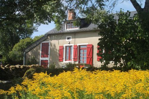 uma casa com persianas vermelhas e um campo de flores amarelas em Gîte de Rangère em Villapourçon