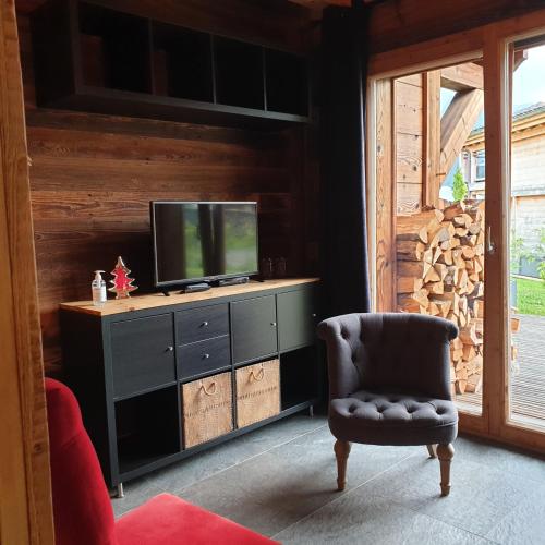 a living room with a television and a chair at Chalet Mary in Essert-Romand