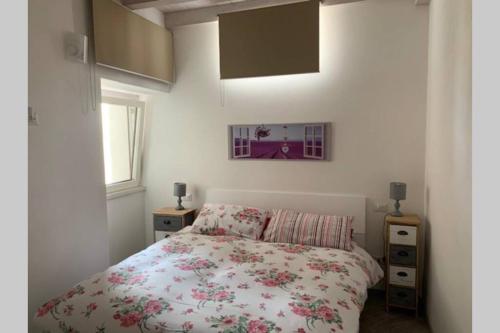 una camera da letto con un letto con copriletto floreale di Casetta al Portico, relax e tranquillità a Porlezza