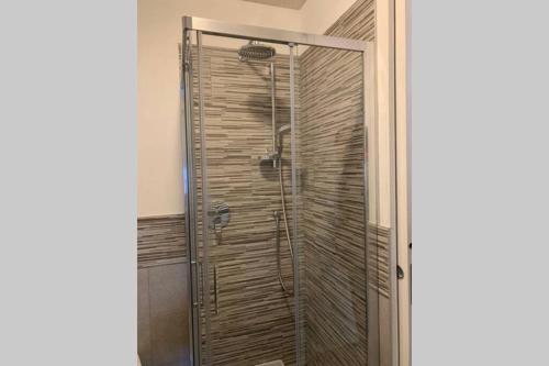 La salle de bains est pourvue d'une douche avec une porte en verre. dans l'établissement Casetta al Portico, relax e tranquillità, à Porlezza