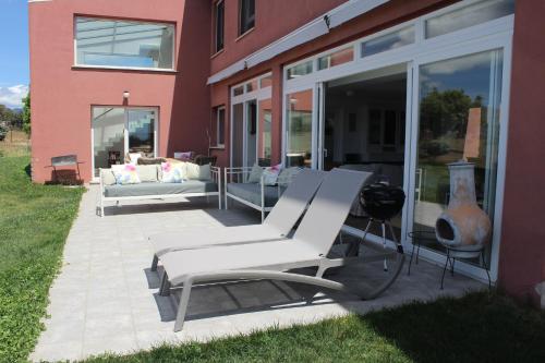 a patio with two white chairs and a couch on it at Finca el enebro in Valdemorillo