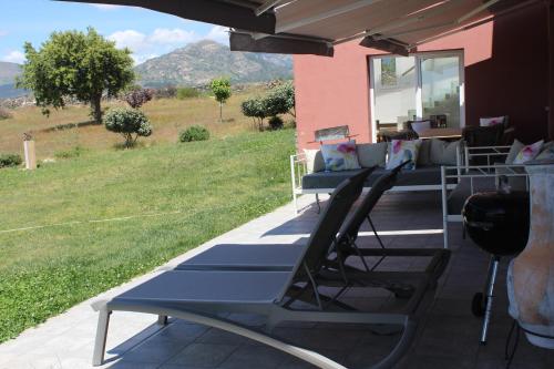a group of lounge chairs on a patio with a view of a field at Finca el enebro in Valdemorillo