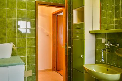 a green bathroom with a sink and a mirror at Apartman Gabrijela in Senj