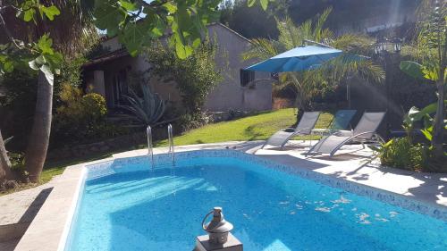 une piscine avec deux chaises et un parasol dans l'établissement Appartement Rez de Jardin avec piscine, à Mandelieu-la-Napoule