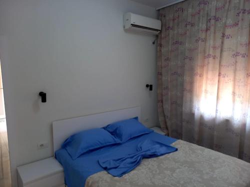 um quarto com uma cama com almofadas azuis e uma janela em Stella Marina Family Apartment 2 em Dhërmi