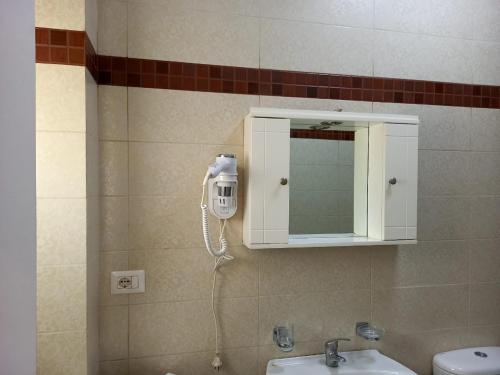 uma casa de banho com um espelho e um telefone na parede em Stella Marina Family Apartment 2 em Dhërmi