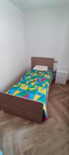 a bed with a colorful comforter in a room at Manuel Guesthouse Arta terme in Arta Terme