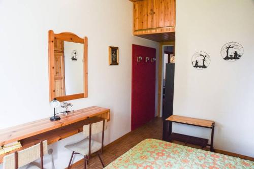 1 dormitorio con escritorio, espejo y cama en Casetta Anita en Cavalese