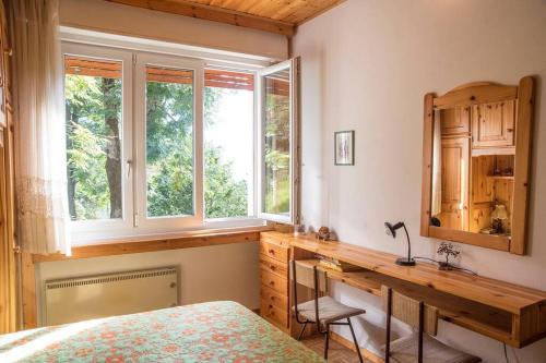 1 dormitorio con escritorio, 1 cama y ventana en Casetta Anita en Cavalese