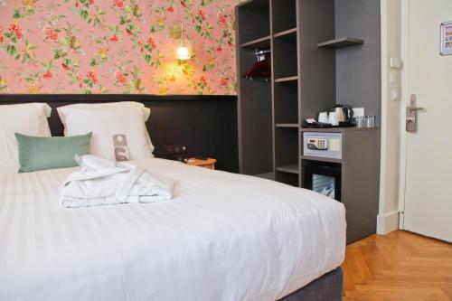a bedroom with a white bed with a pink wall at Hotel La Villa Nice Promenade in Nice