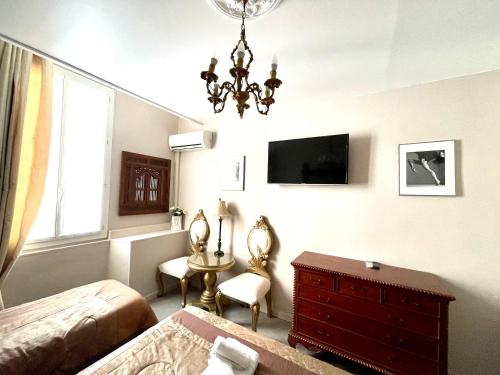 a bedroom with a bed and a dresser and a television at Hotel le Romanesque in Cannes