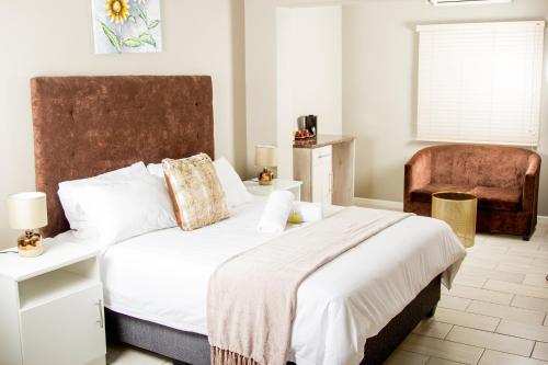 Un dormitorio con una cama grande y una silla. en 103onWallace Self Catering Guest House, en Ciudad del Cabo