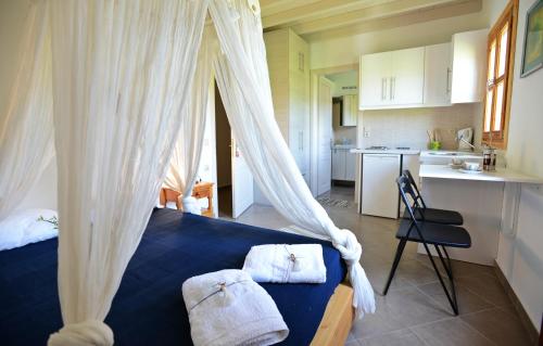 a bedroom with a blue bed with curtains and a kitchen at Filio Apartments in Kámbos