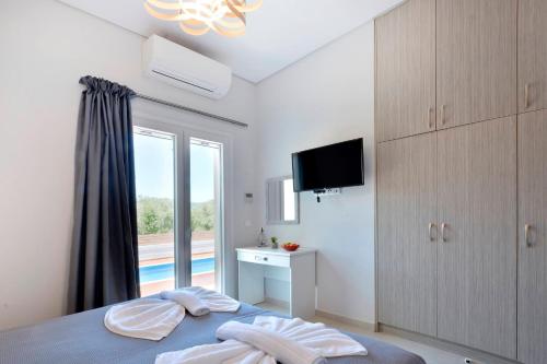 a bedroom with a bed and a tv and a window at Villa Bratou in Episkopianá