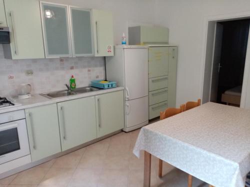 a kitchen with white cabinets and a table and a sink at Apartments Anita Hure in Hvar