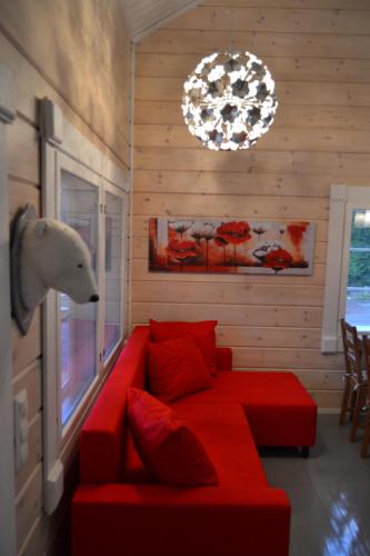 a living room with a red couch and a lamp at Pikku Torppa Cottage in Kotka