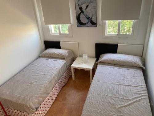 two beds in a room with a table and two windows at Sevilla Saltera casa RURAL cerca centro de Sevilla Familiar - Trabajo - Wifi in Salteras